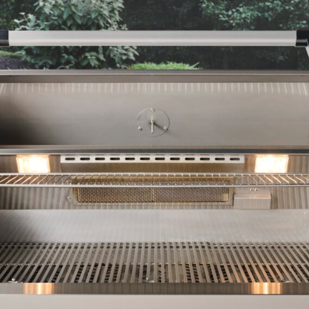 Open built-in gas grill interior with warming rack, burners, and metal heat shield