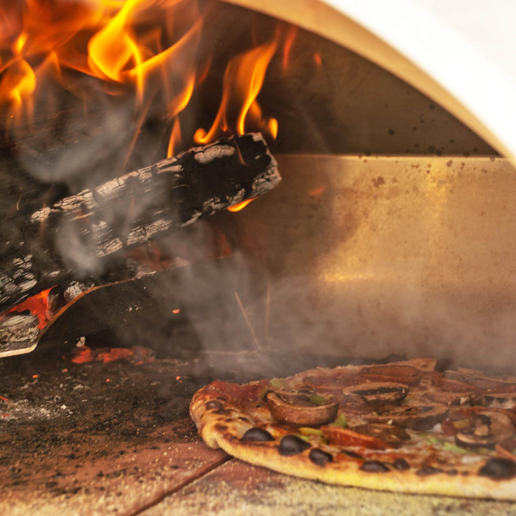 Inside wood-fired pizza oven showing active flames over burning logs