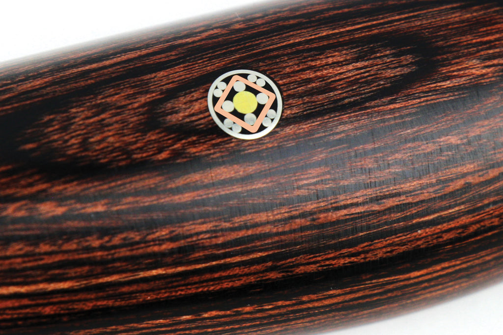 Decorative circular inlay on dark wooden knife handle with red accent trim