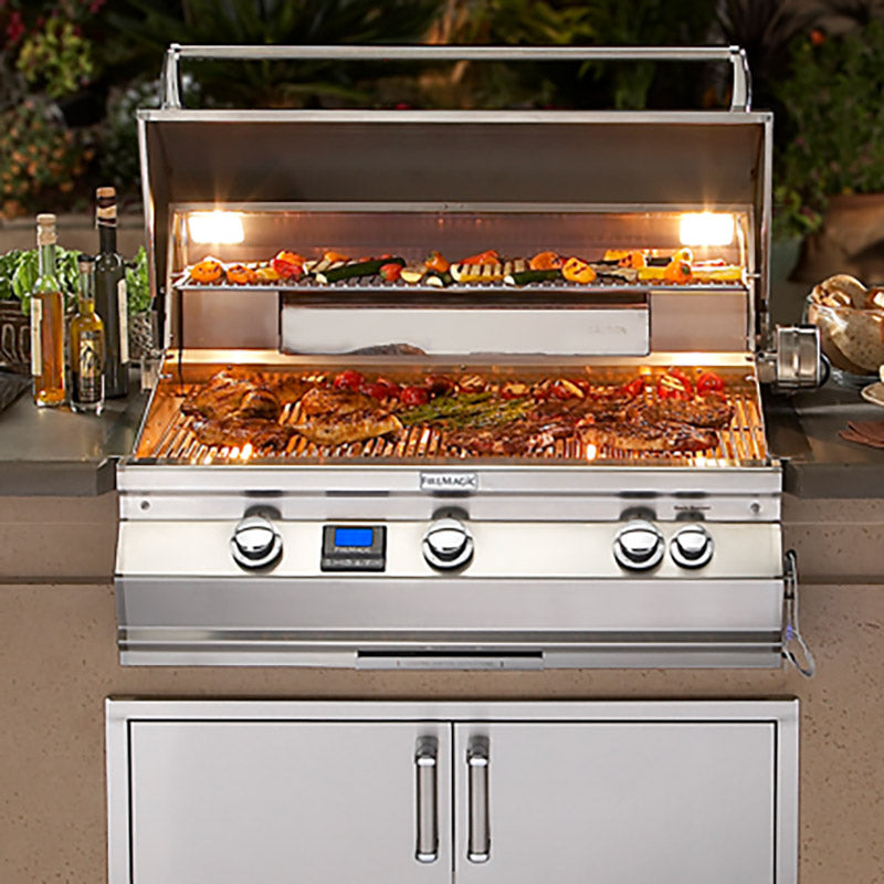 Built-in gas grill with open hood, lit burners, and food-ready cooking grates
