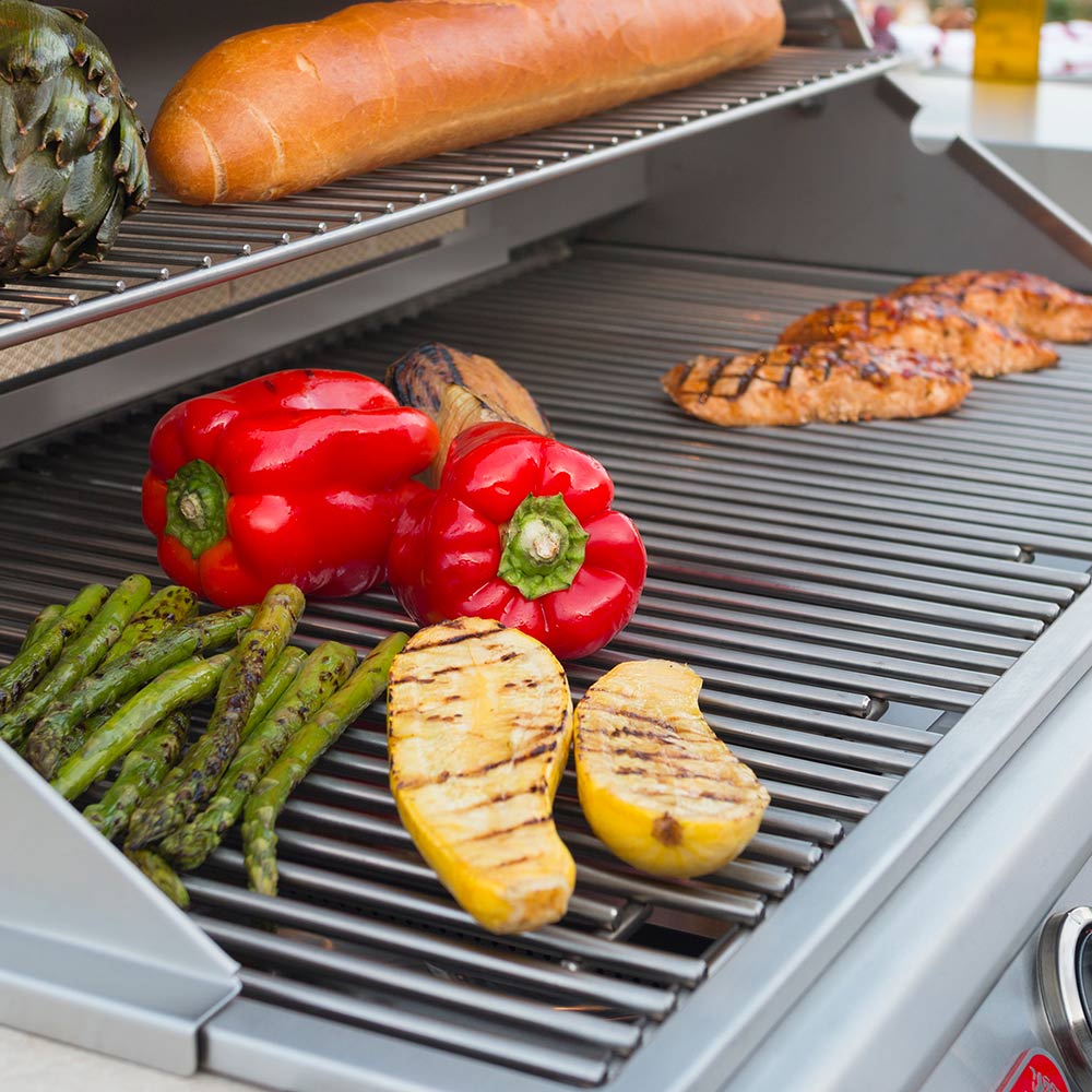 Grill cooking grate with red peppers, asparagus, onion slices, and potatoes