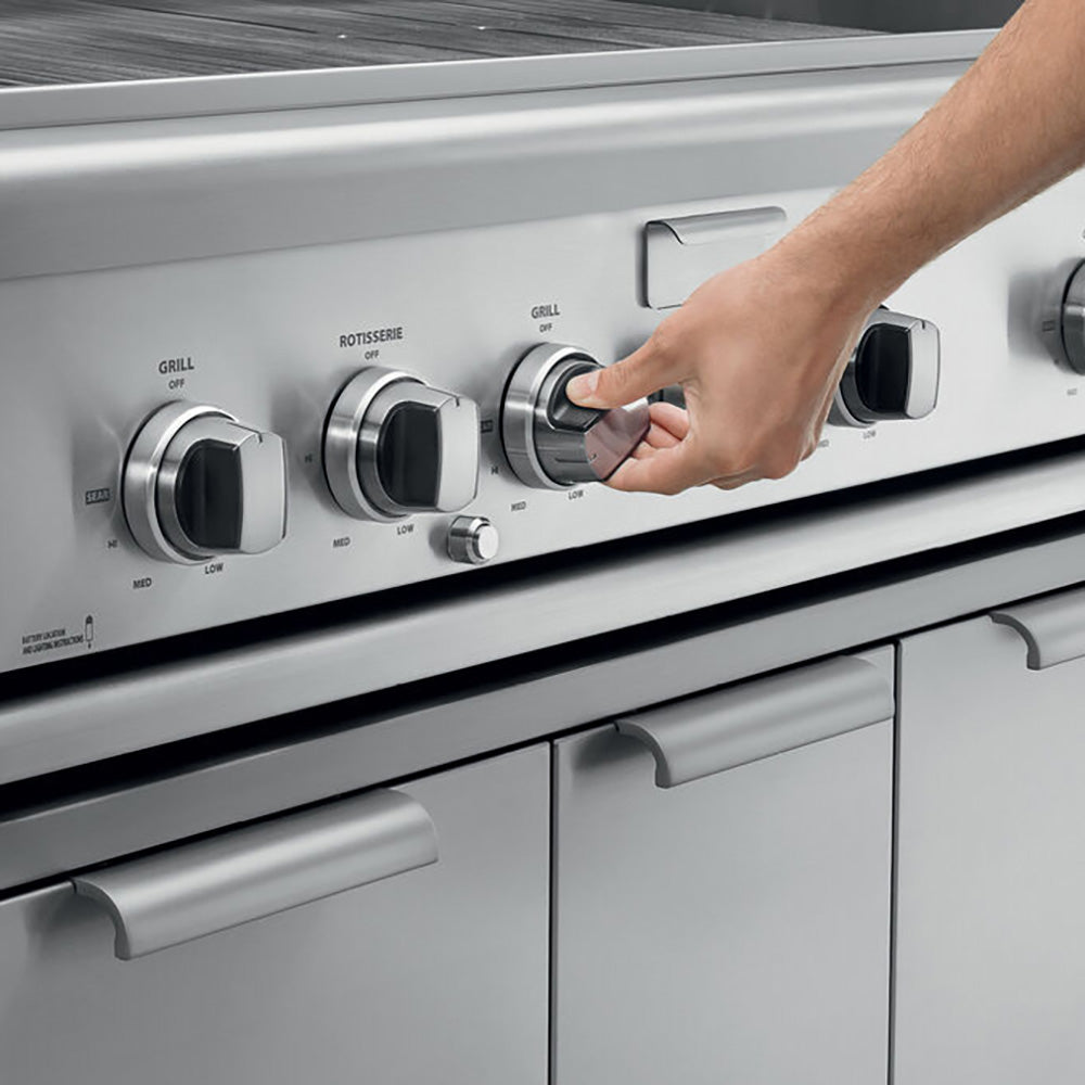 Built-in gas grill control panel with three knobs, including hand turning a burner control