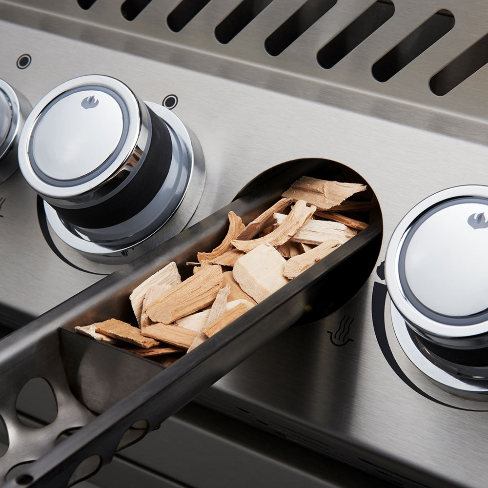 Wood chip tray and stainless burner area with two front control knobs inside grill.