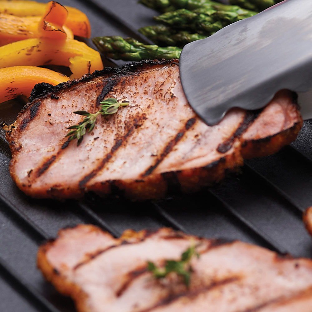 Cooked pork slices on black cast iron griddle with spatula