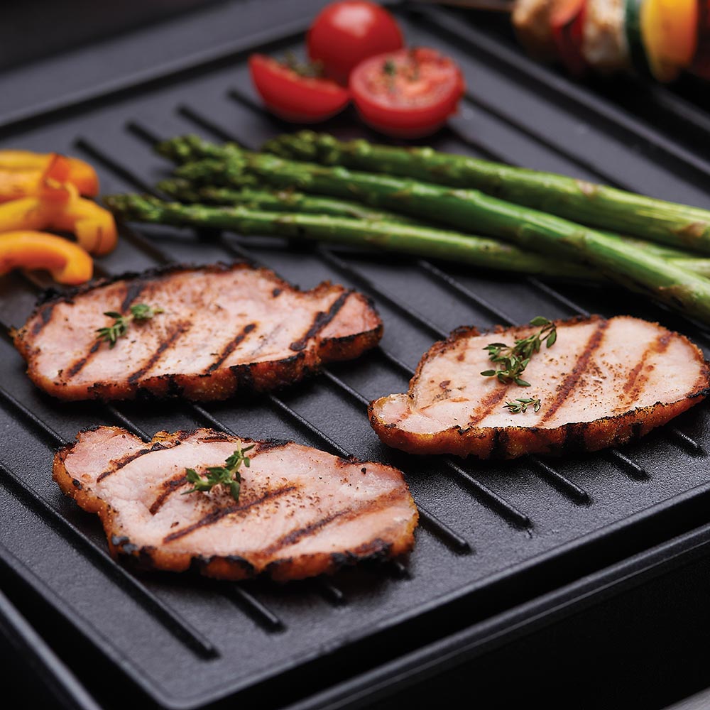 Black cast iron griddle with raised ridges and cooked food on surface