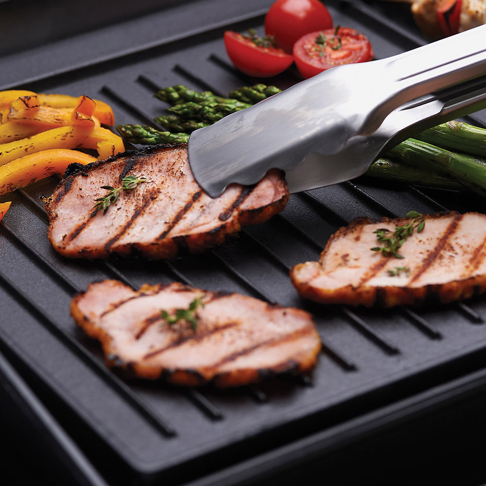 Black cast iron griddle with ridged surface and metal spatula over steaks