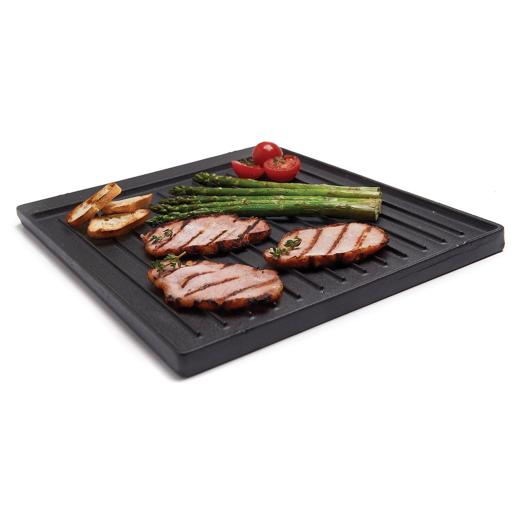 Cast iron griddle with ridges, holding grilled vegetables and sliced meat