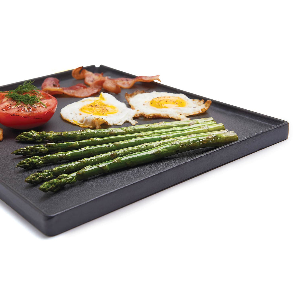 Cast iron griddle with ridges, topped with asparagus, tomatoes, and fried eggs