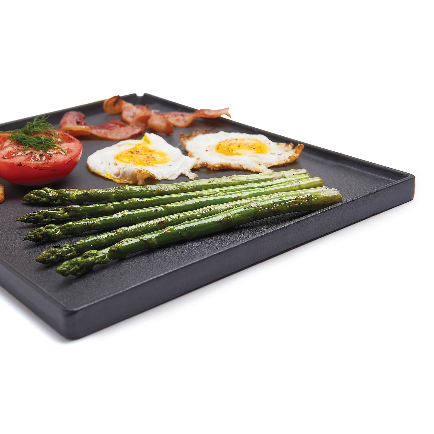 Cast iron griddle with ridges, topped with asparagus, tomatoes, and fried eggs