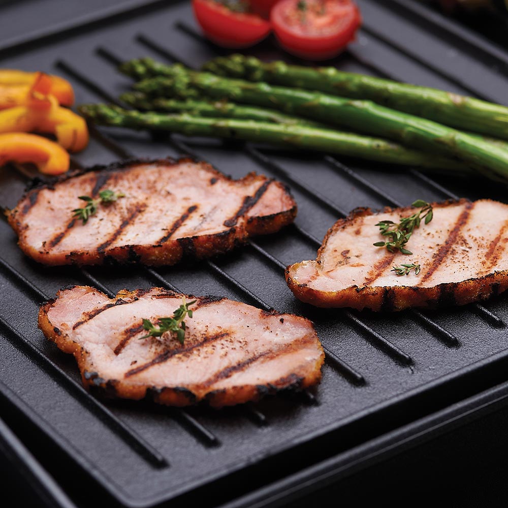 Cast iron griddle with grilled slices, herbs, and green asparagus
