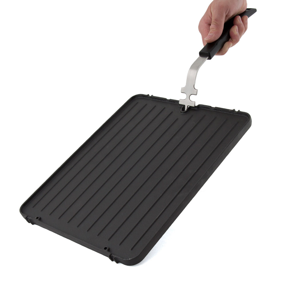 Cast iron griddle with ridged surface held by a metal support tool