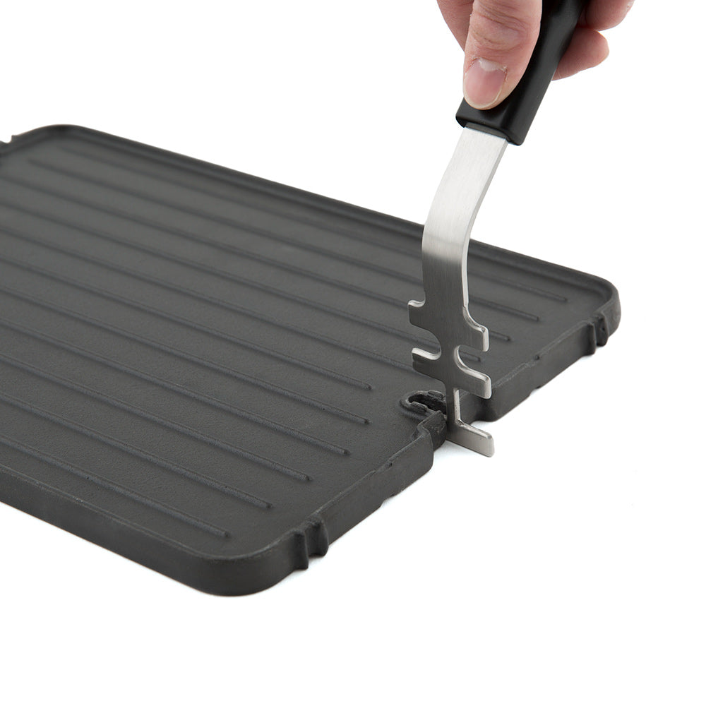 Cast iron griddle with ridged surface and metal support tool at edge