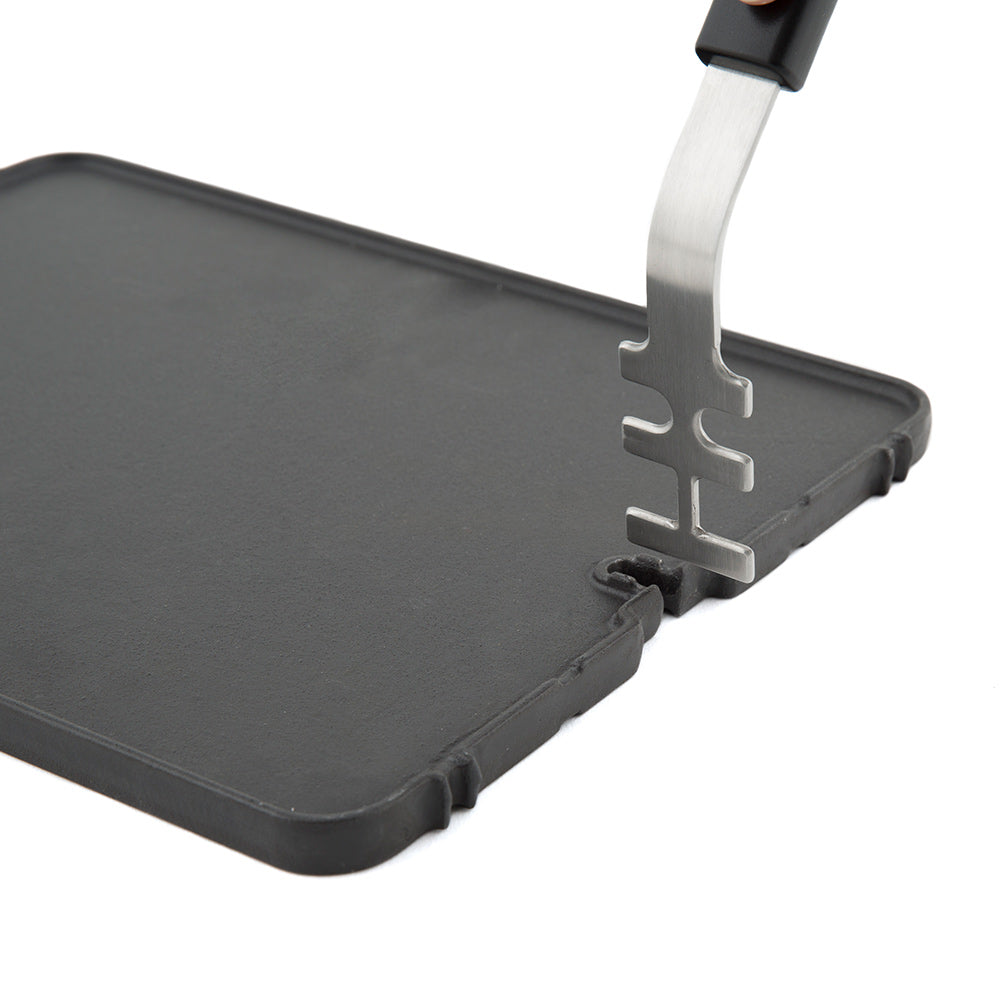 Cast iron griddle with metal support tool resting on the edge