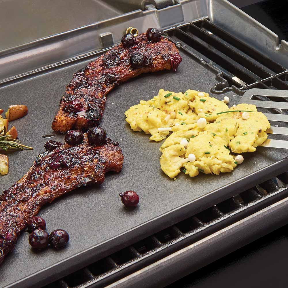 Cast iron griddle with grilled meat and omelet on the ridged surface