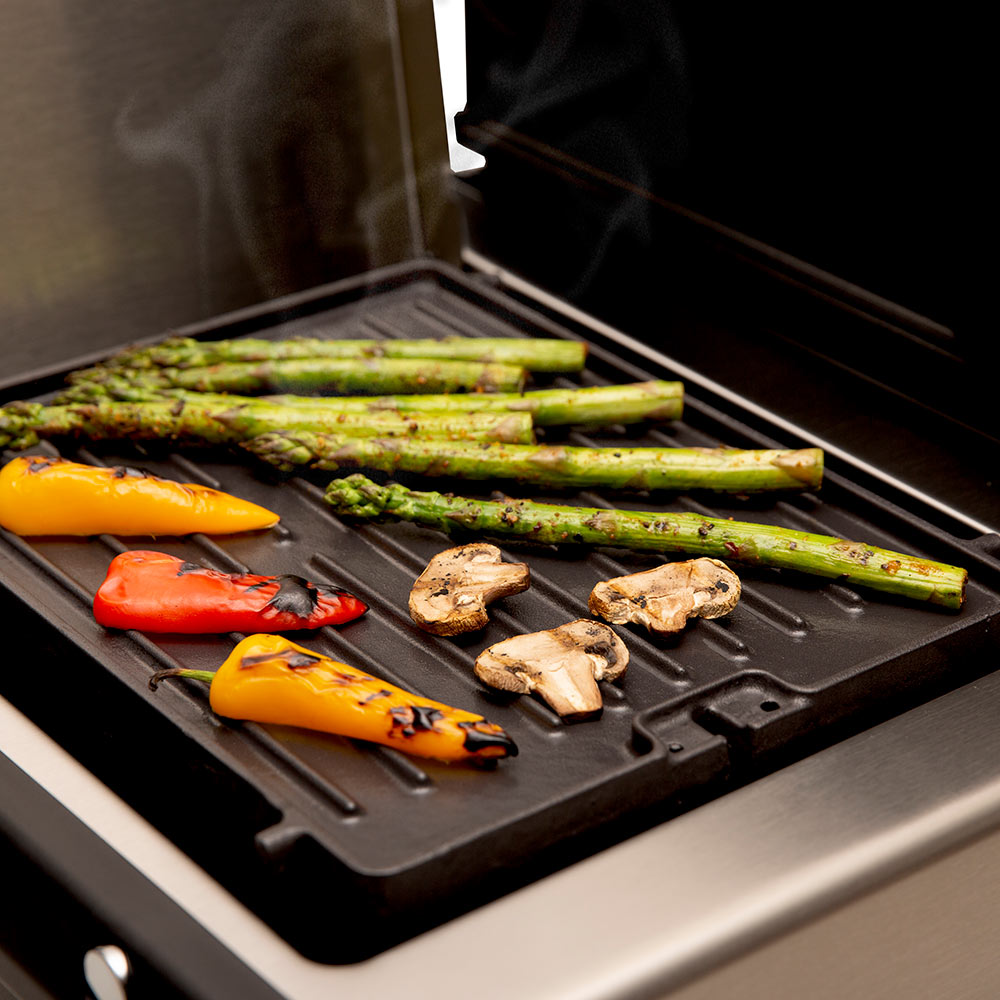 Cast iron side burner griddle with asparagus, peppers, and mushrooms, steam rising