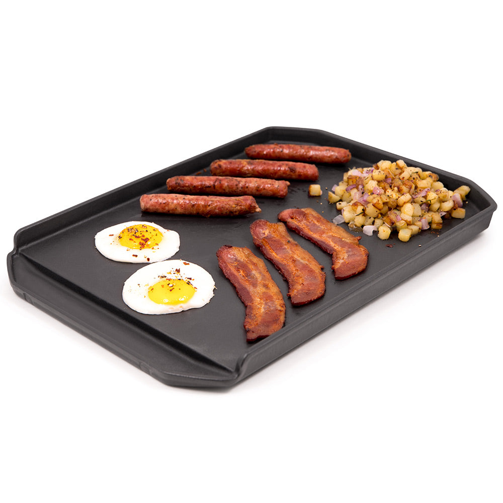 Cast iron griddle plancha with sausage, fried eggs, and diced vegetables