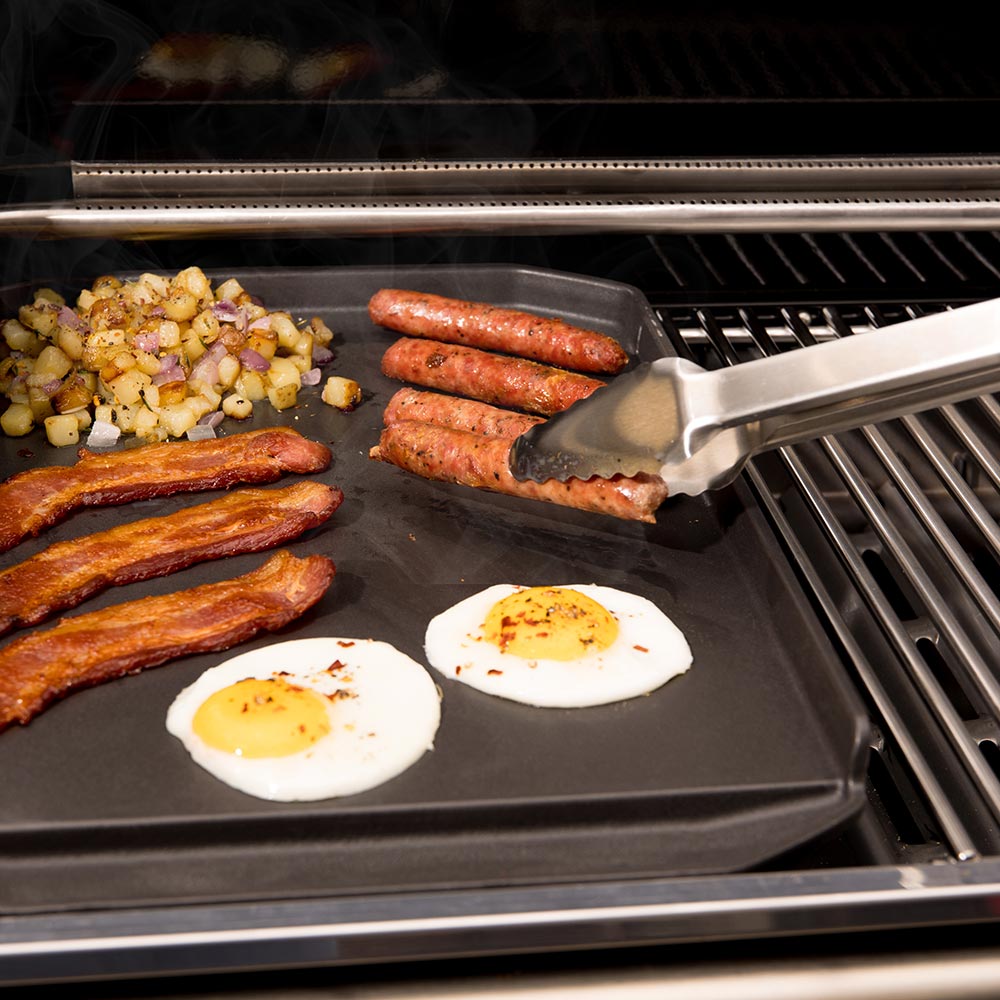 Cast iron griddle plancha with sausages, fried eggs, and diced vegetables