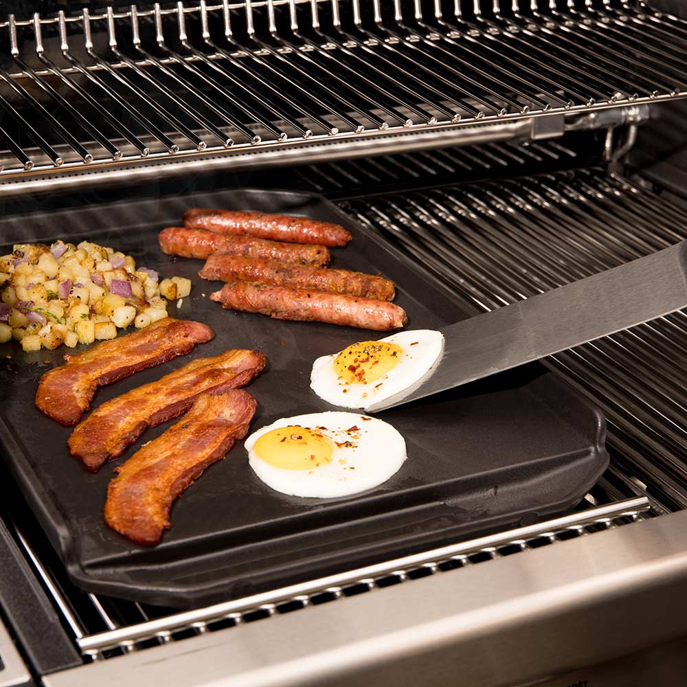 Cast iron griddle plancha over grill with sausages and fried eggs