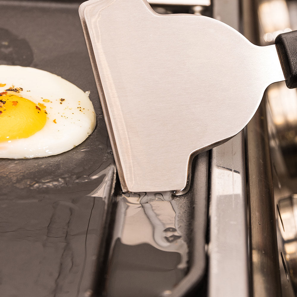 Cast iron griddle plancha with spatula over two fried eggs