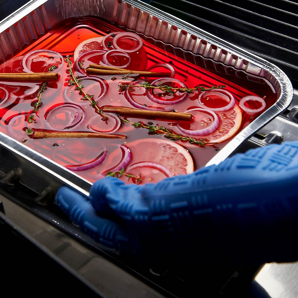 Aluminum drip pan tray filled with red liquid, herbs, and onion slices