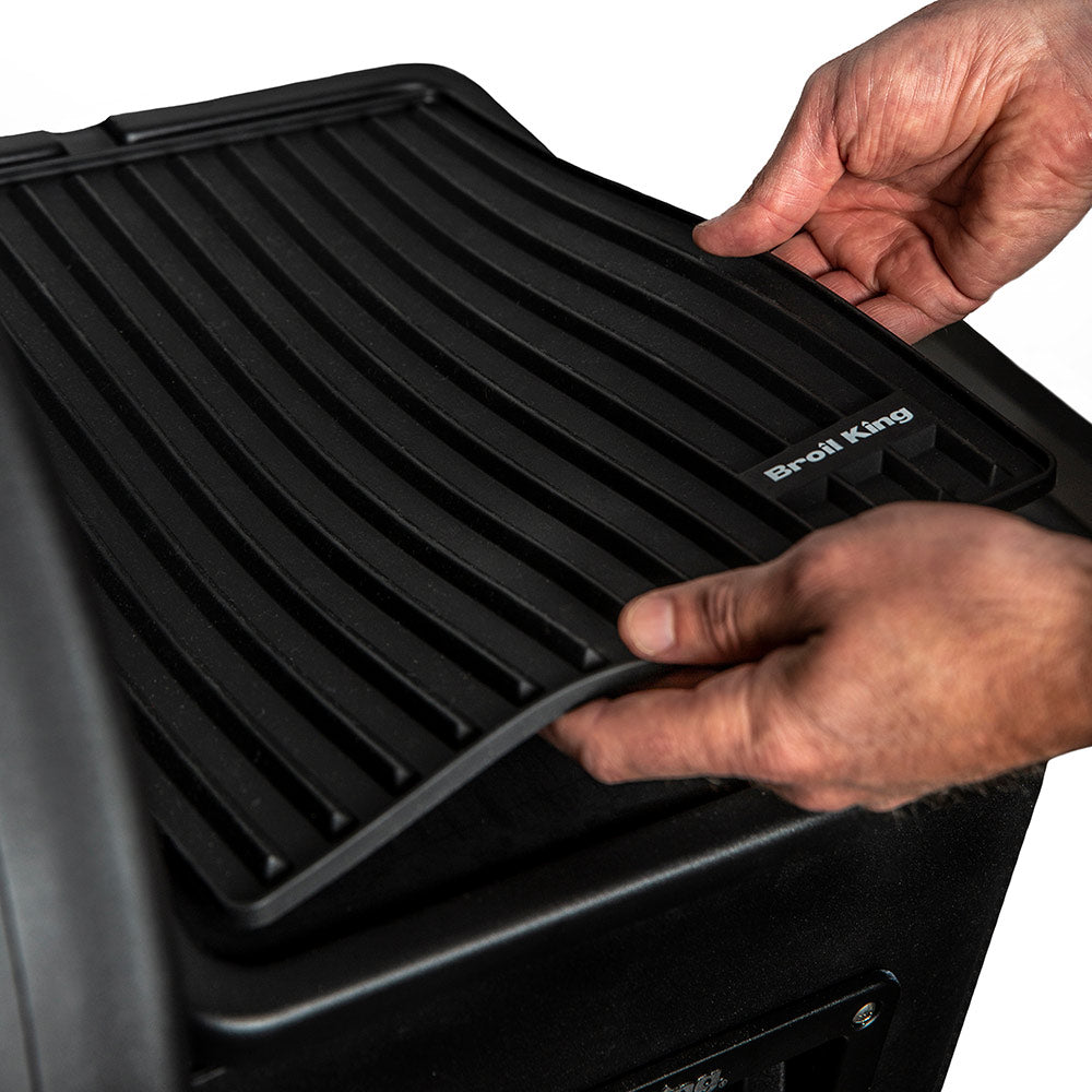 Broil King silicone side shelf mat, black ribbed surface being adjusted by hands