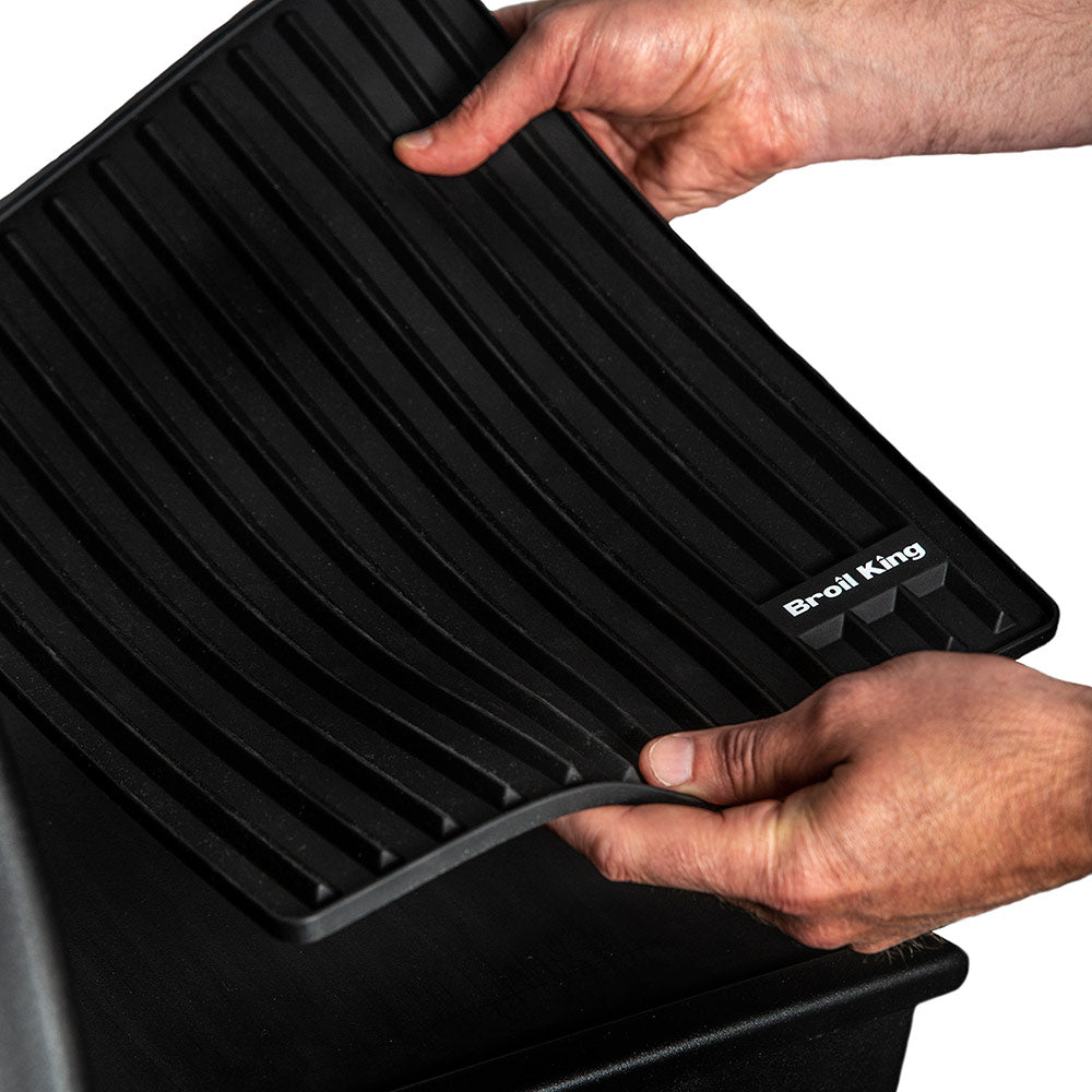 Broil King silicone side shelf mat, black ribbed grill shelf being set in place