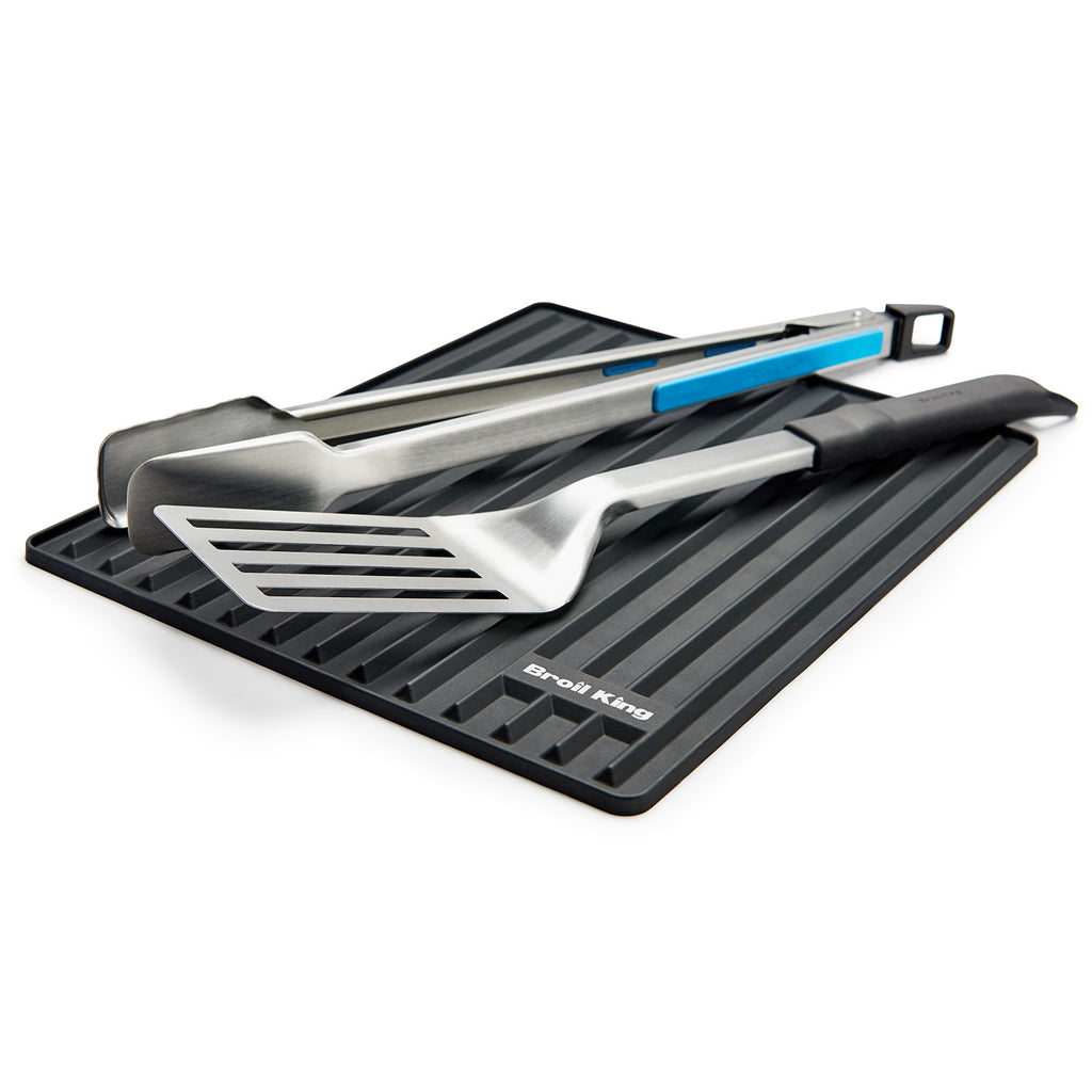 Silicone grill side shelf mat with grill tools resting on dark ribbed surface