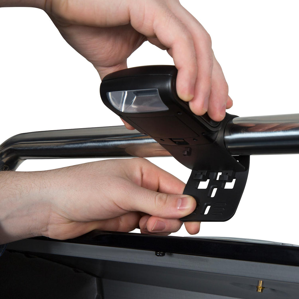 Hand installing a black clamp-on grill light onto a grill tube and frame