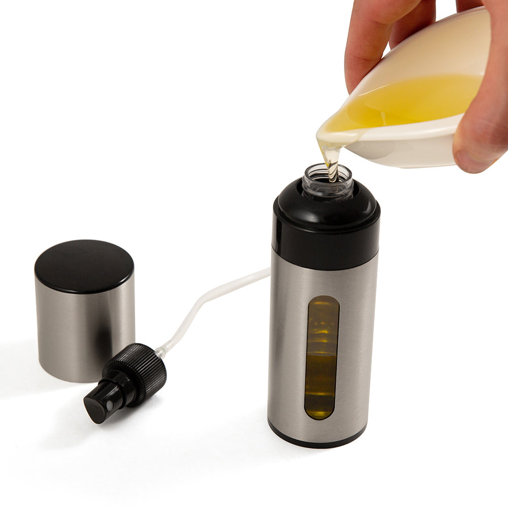 Stainless steel oil spritzer with black nozzle; being filled with yellow oil