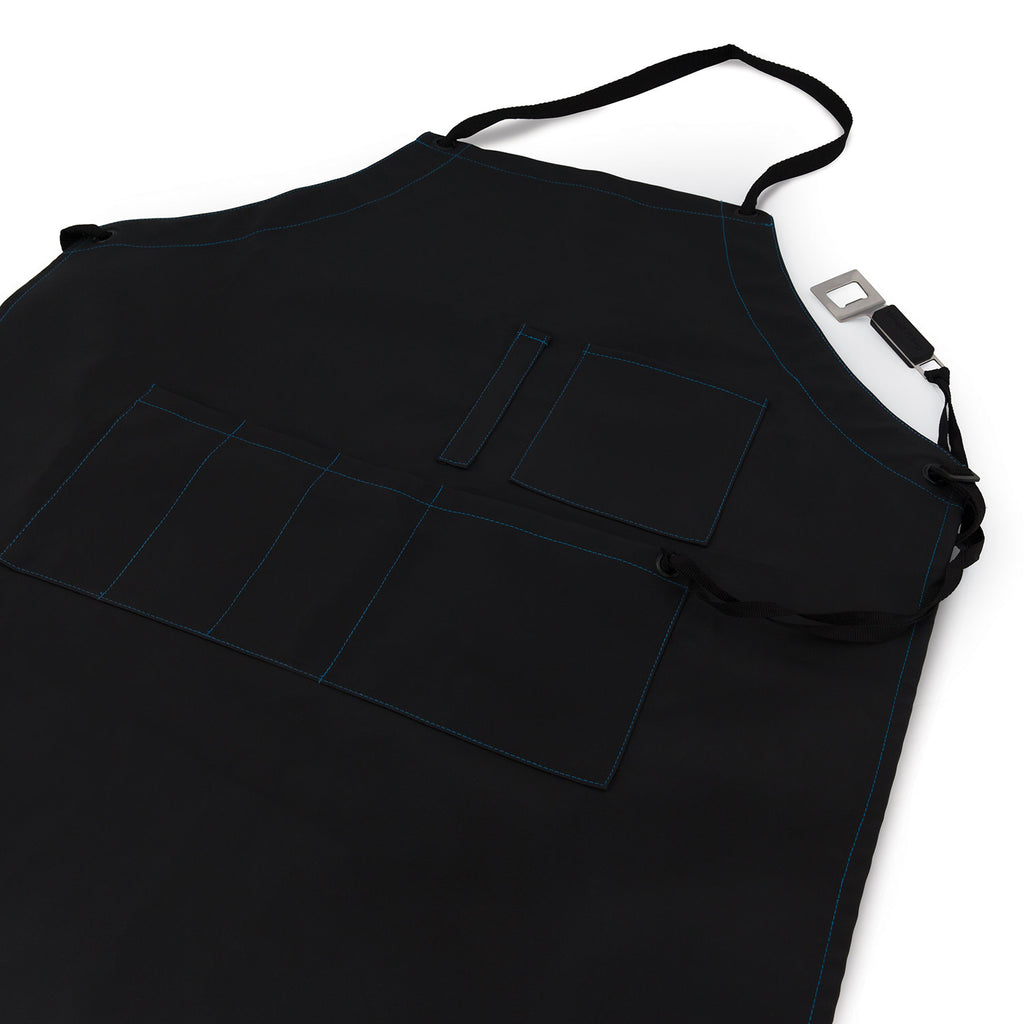 Black grilling apron with stitched panels, front pockets, and adjustable strap