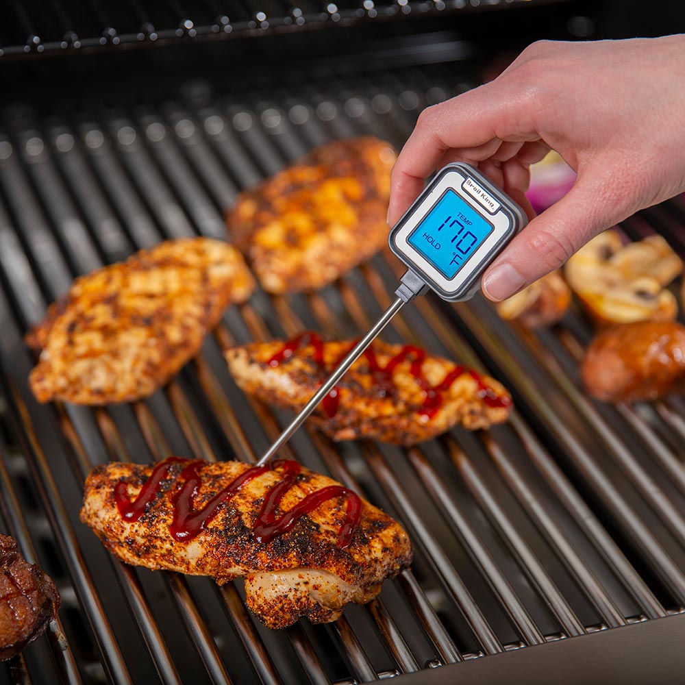Hand holding instant read thermometer with stainless probe, blue LCD showing temperature