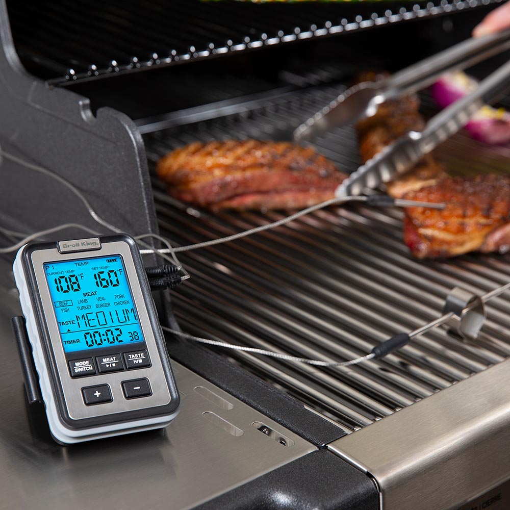 Broil King thermometer showing temperature on grill while probes touch steaks