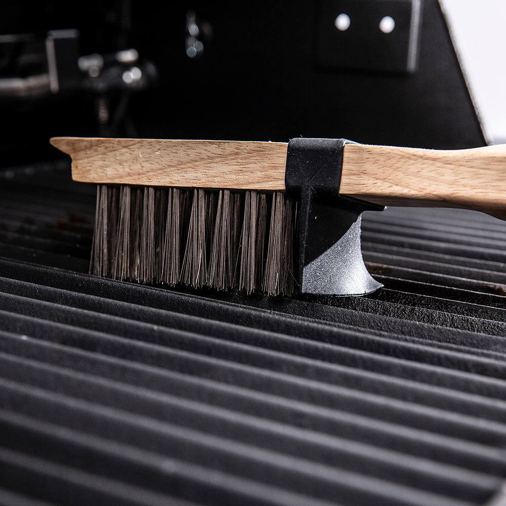 Grill brush with wooden handle, black bristles, and angled scraper