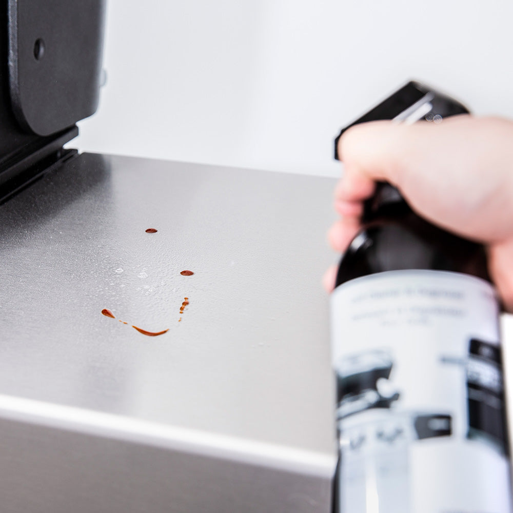 Grill surface being sprayed with cleaner, showing loosened grease spots