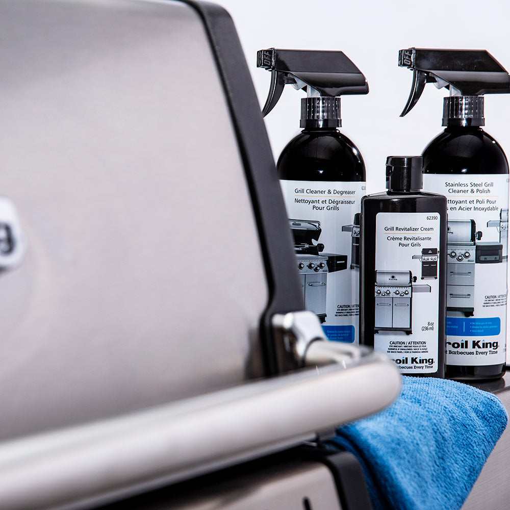 Broil King grill revitalizer cream bottles with spray triggers near grill control panel