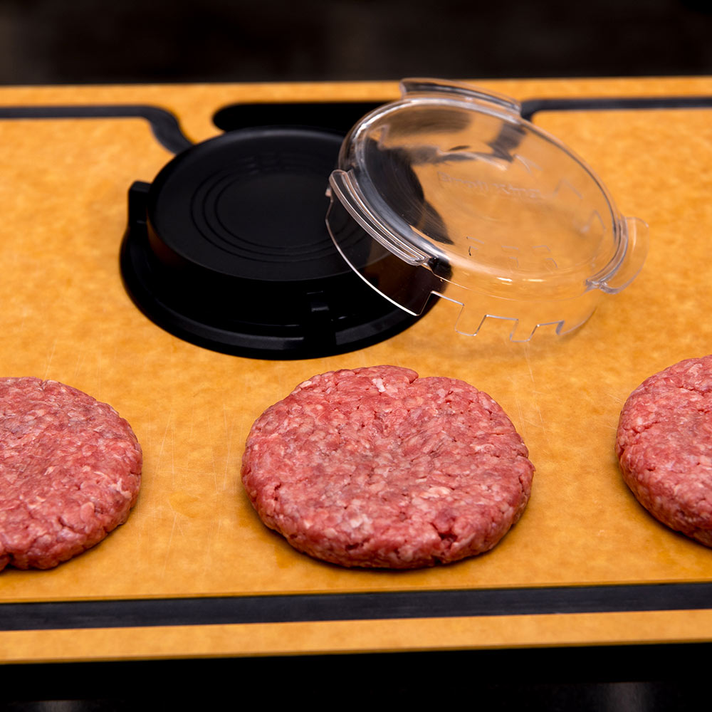 Burger press parts with raw burger patties on a flat grilling tray