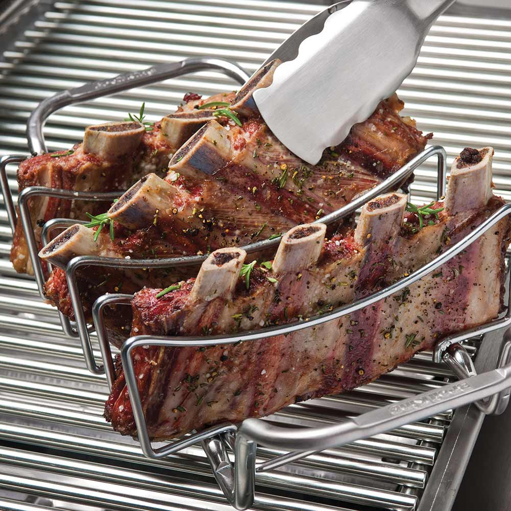 Stainless rib and roast rack holding seasoned rib pieces with herbs on grill