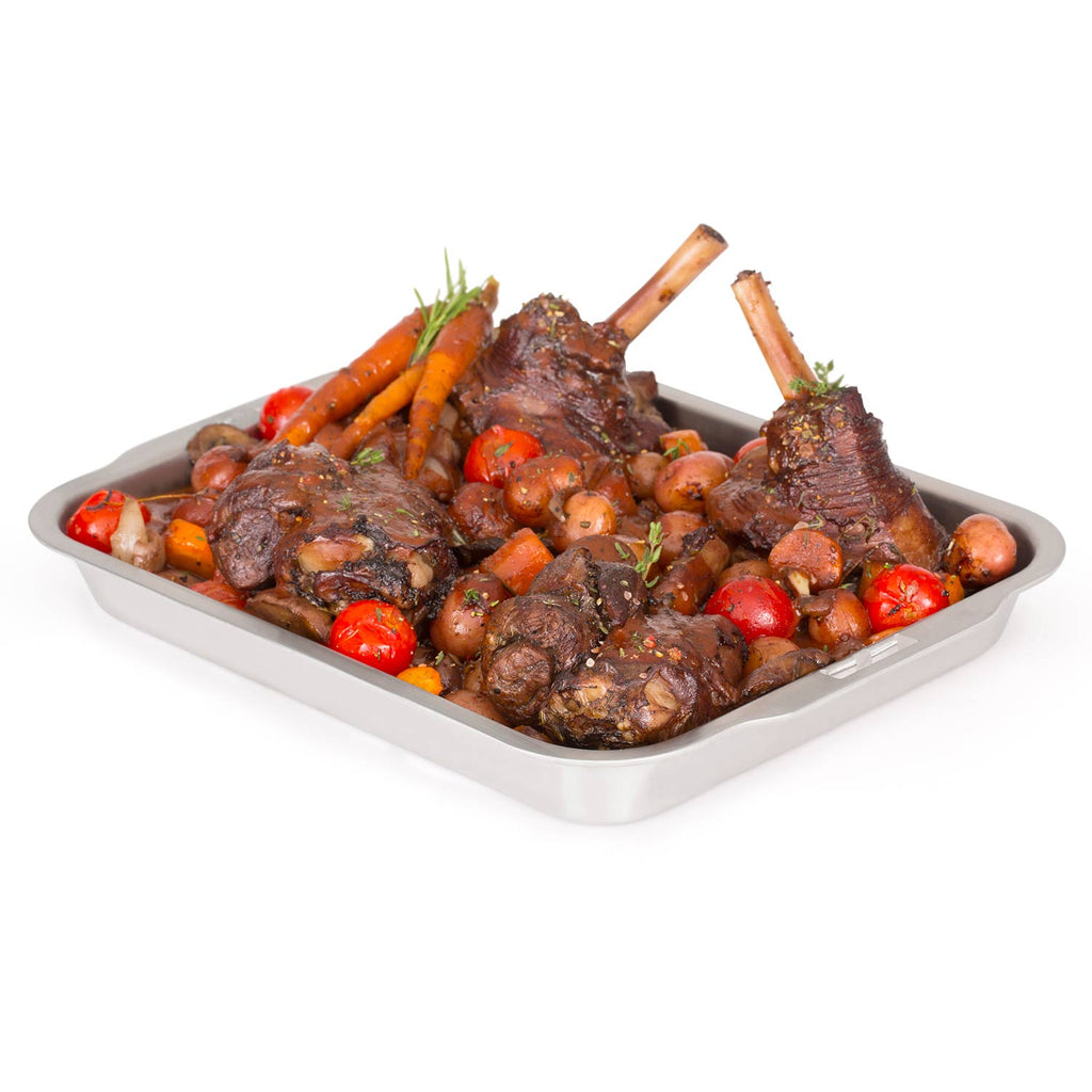 Stainless steel roasting and drip pan with ribs, tomatoes, and herbs