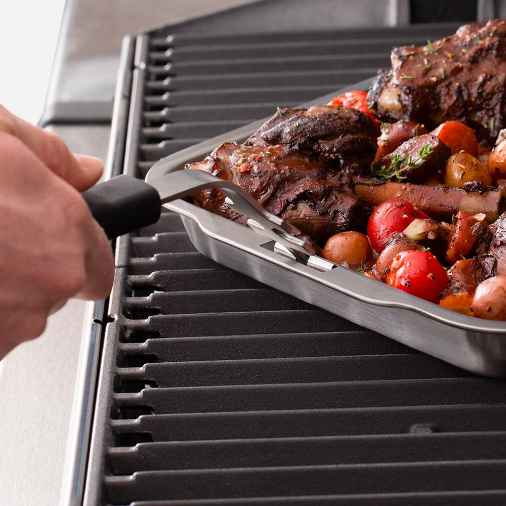 Stainless steel roasting and drip pan on grill with ribs and roasted tomatoes