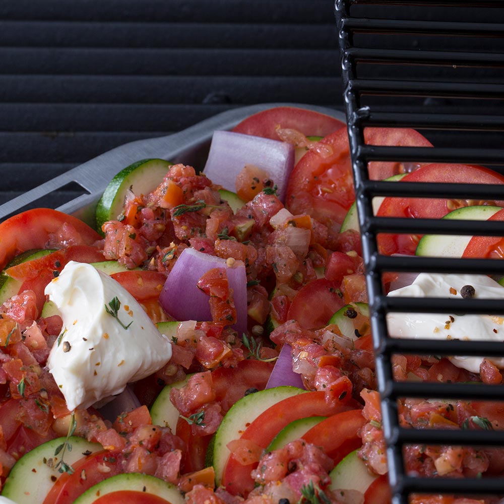 Stainless steel roasting and drip pan on grill with tomato-vegetable topping