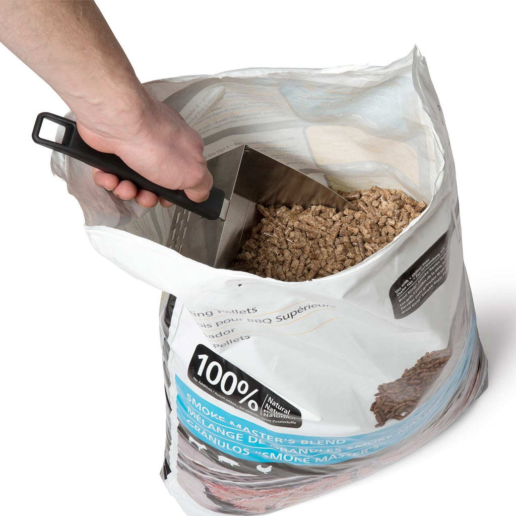 Hand uses metal scoop with black handle to scoop dark pellets from a bag