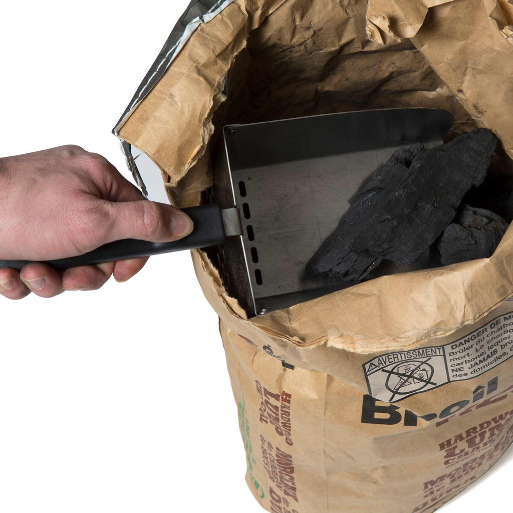 Metal scoop held over a paper bag, showing dark pellets and black handle