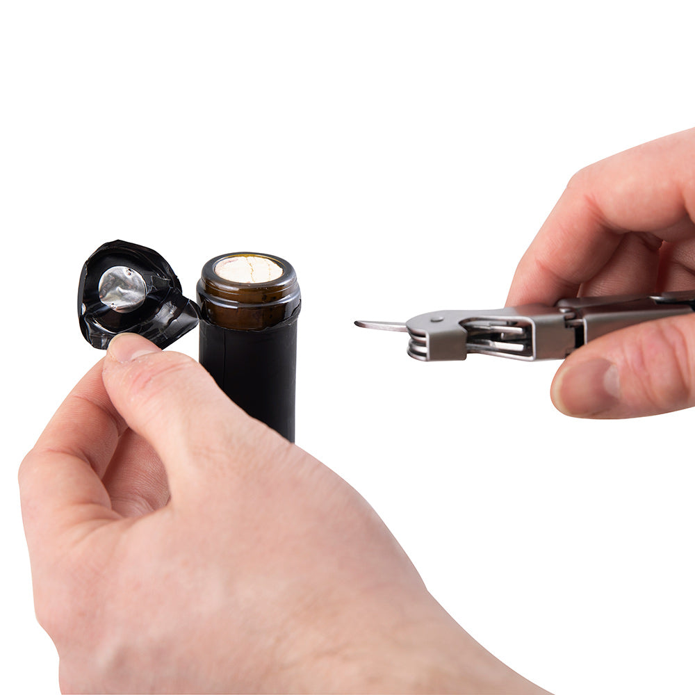 Wine bottle opener lifting cork from dark wine bottle using the corkscrew.