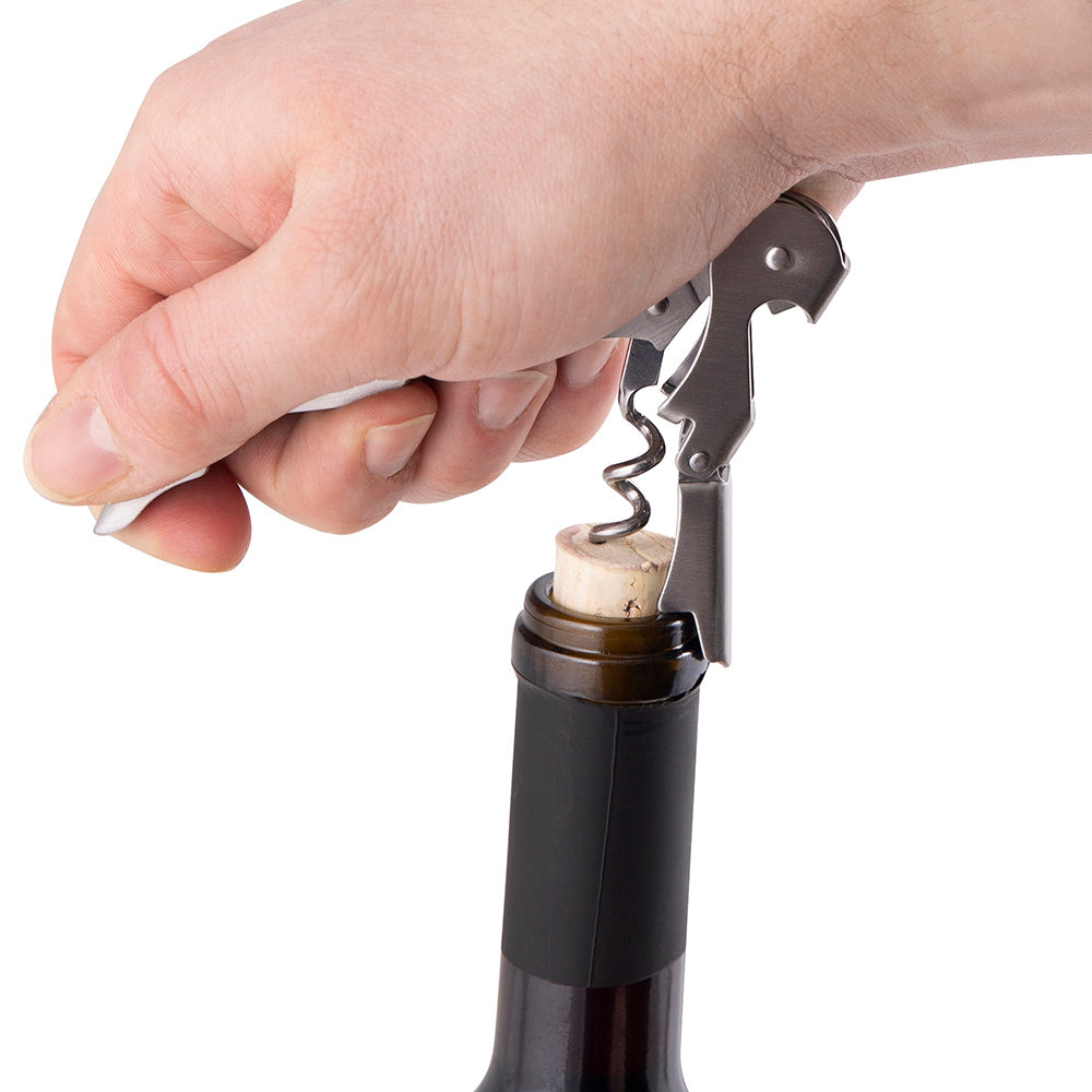 Wine bottle opener with corkscrew in bottle neck, hands pulling lever to lift cork.