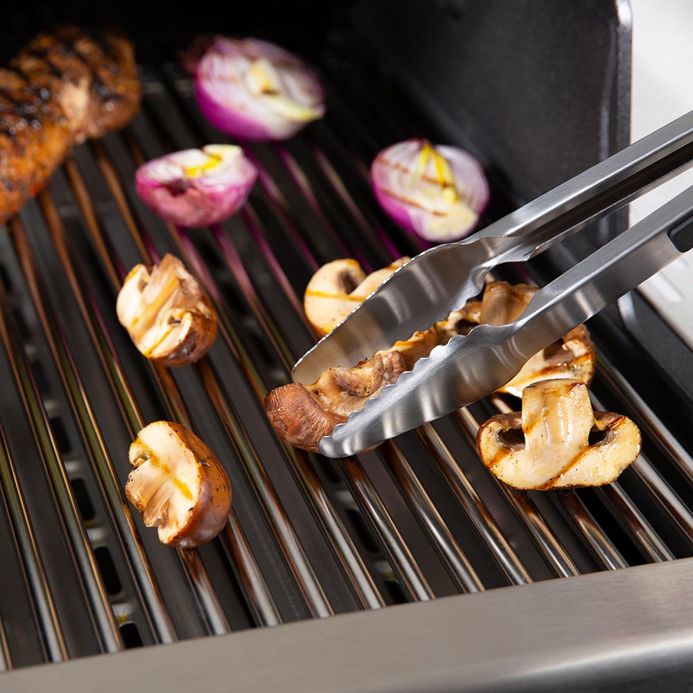 Broil King baron grill tongs lifting sliced vegetables from the grill