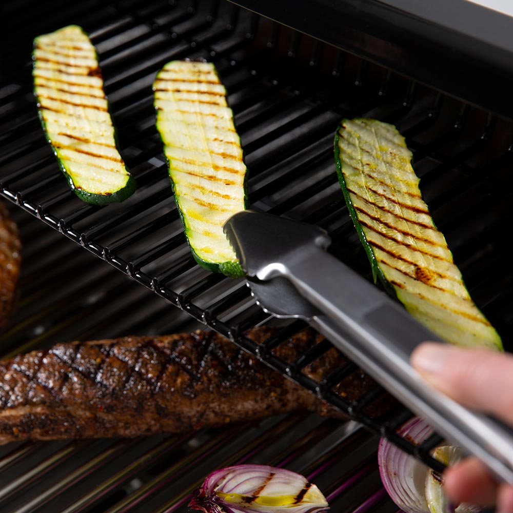 Broil King grill tongs turning zucchini and other grilled foods on the grate