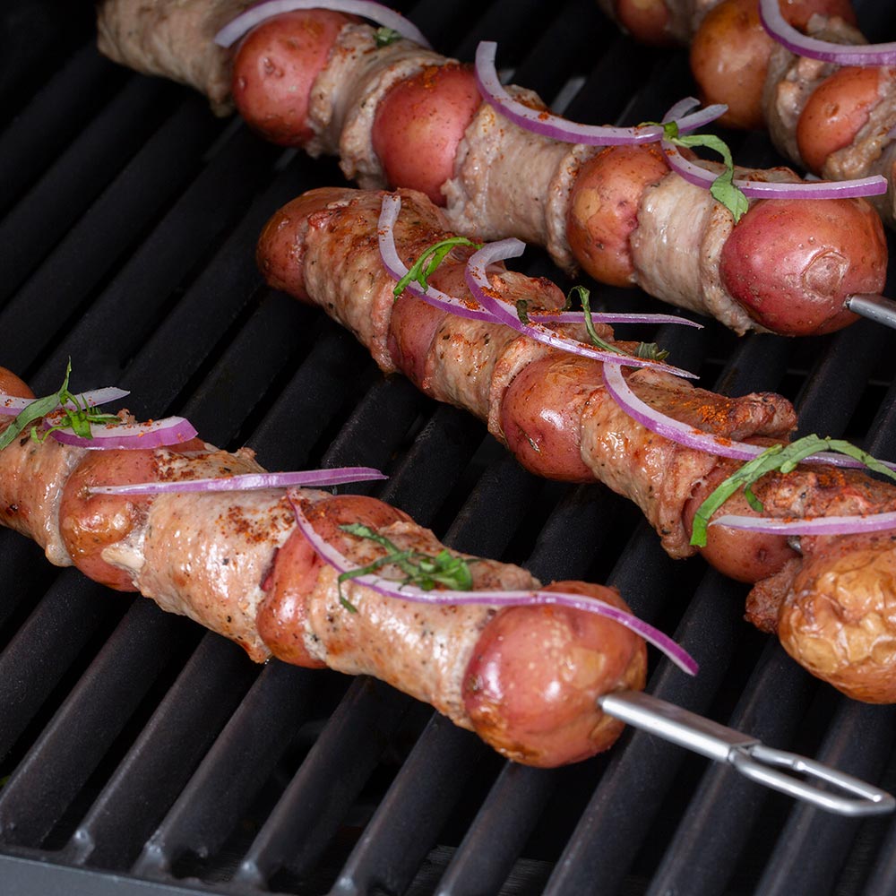 Stainless steel dual-prong skewers with sausages on the grill