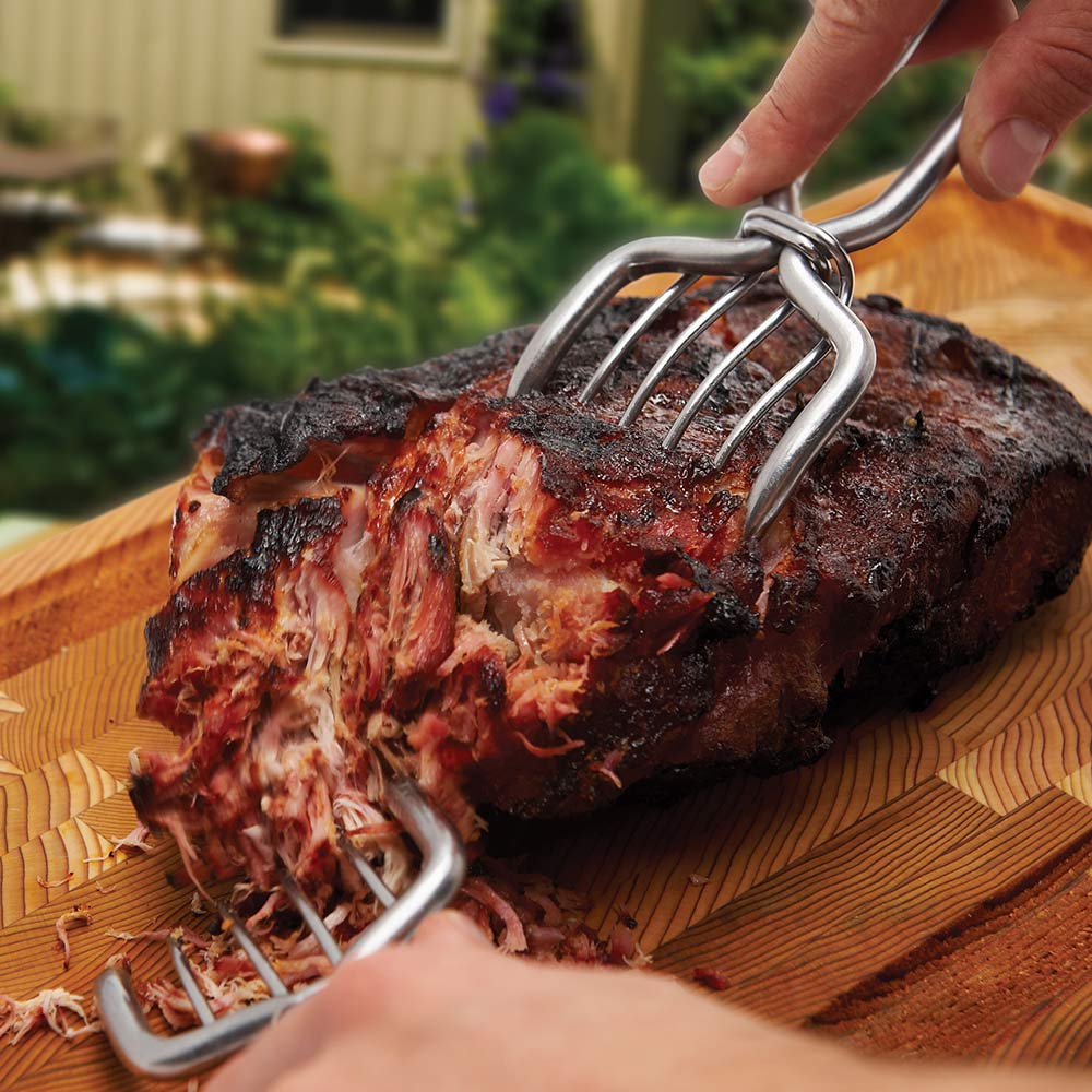 Stainless steel pork claws gripping a sliced pork roast for shredding