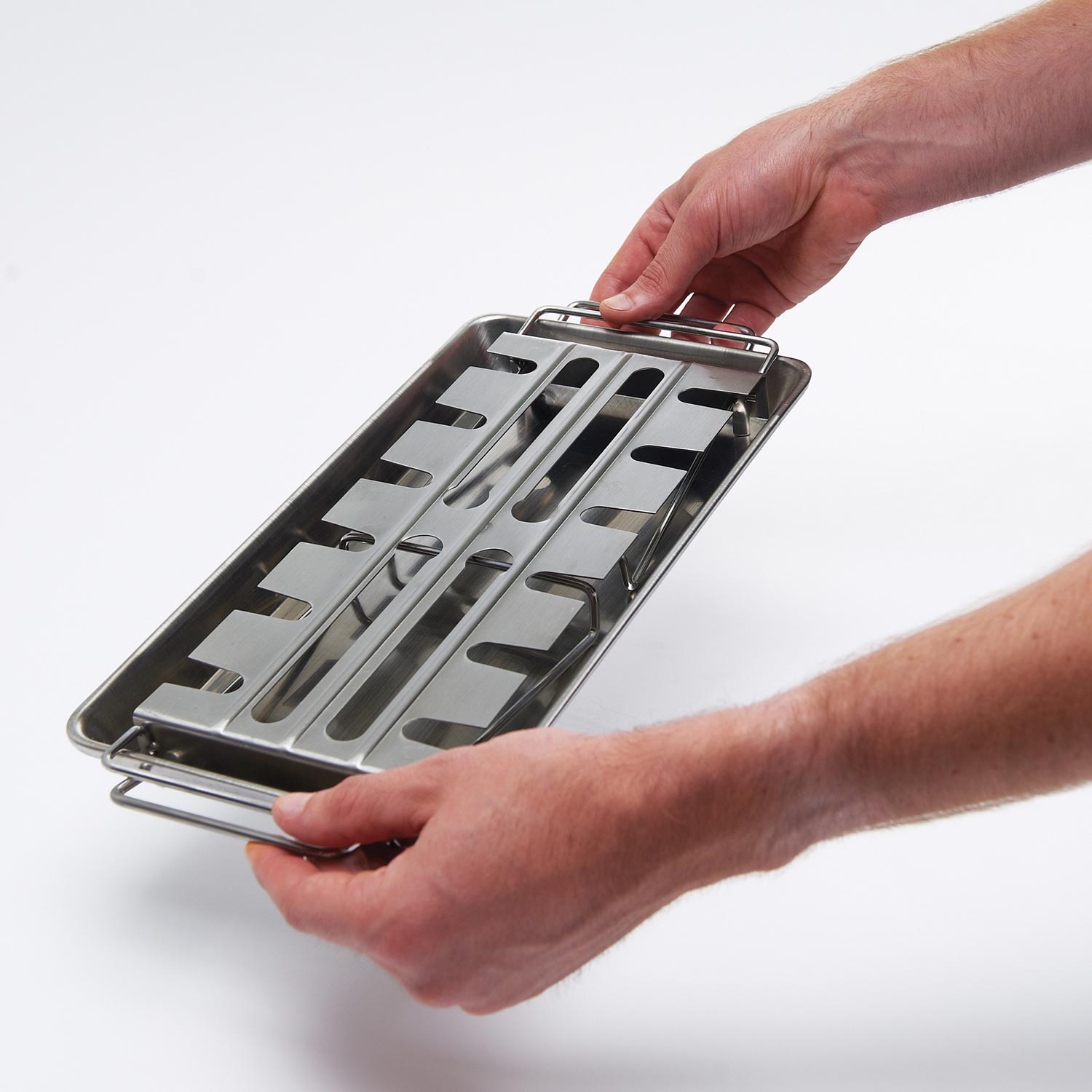 Stainless steel wing rack held by hands, featuring a slotted roasting grid