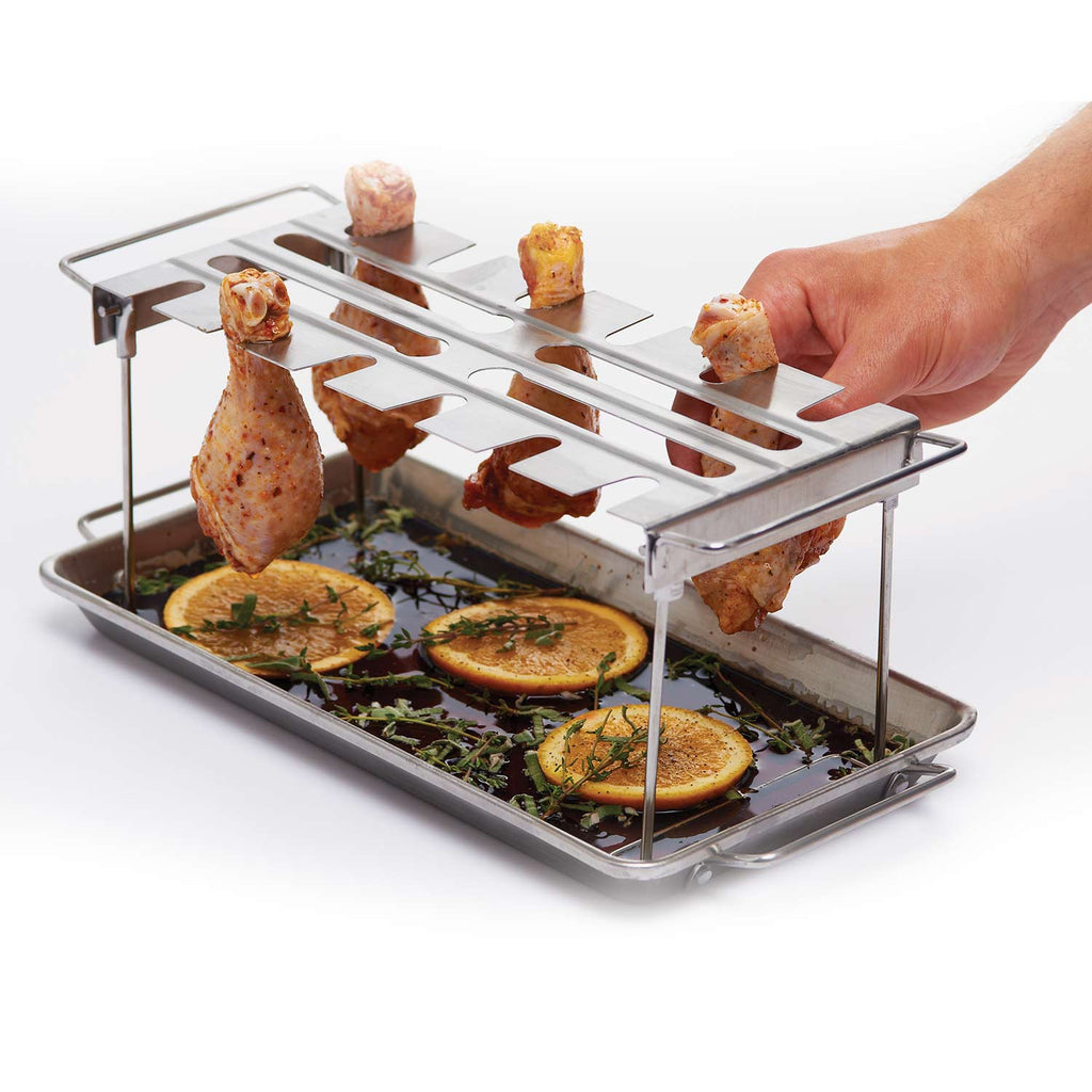 Stainless steel wing rack and drip pan holding wings with orange slices on the grid